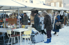 851896 Afbeelding van enkele kramen met publiek op de rommelmarkt, gehouden op een besneeuwd braakliggend terrein bij ...